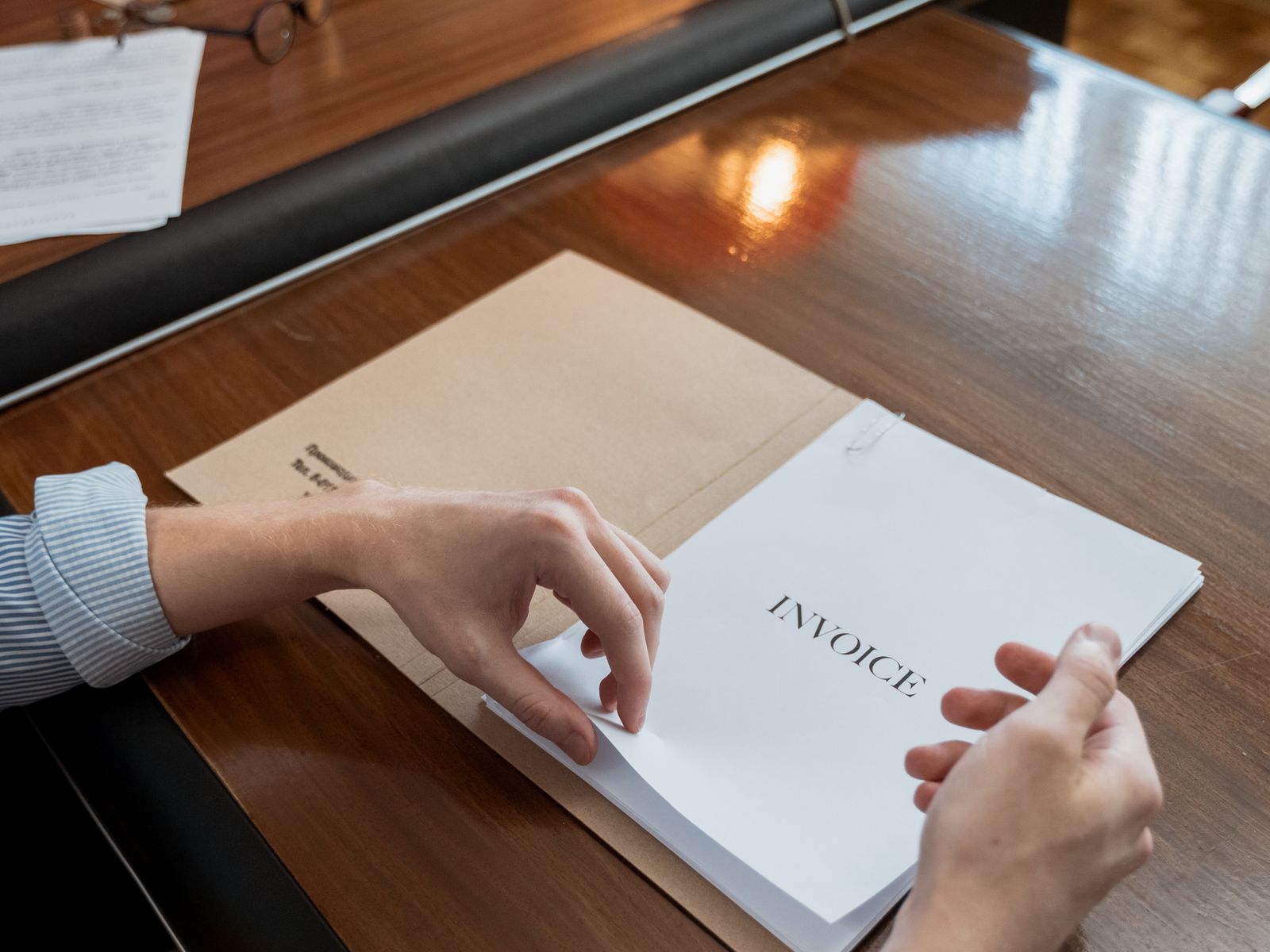 Hands sorting a stack of small supplier invoices